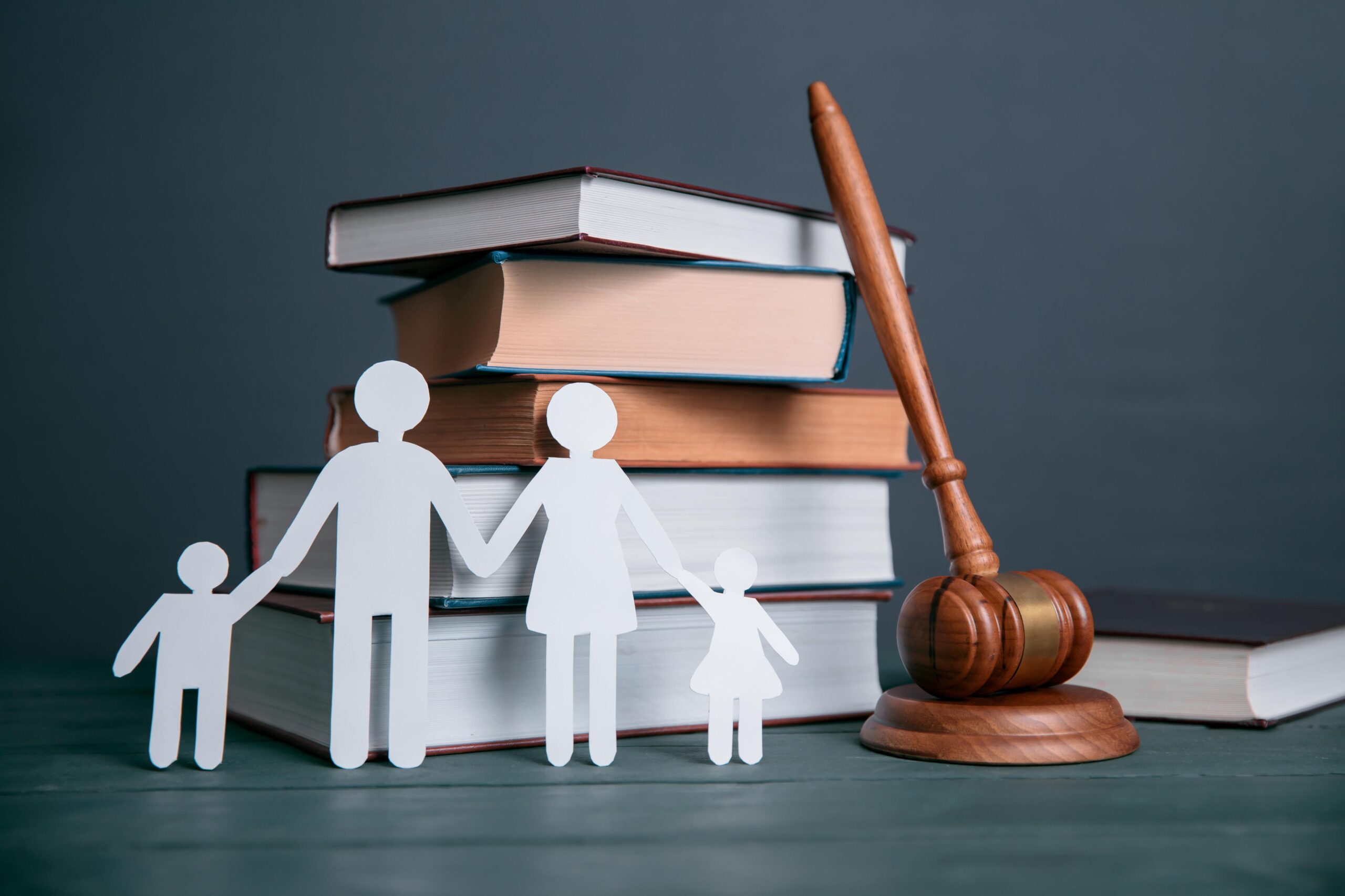 Tomo de libros legales junto a un mazo y un recortable de familia